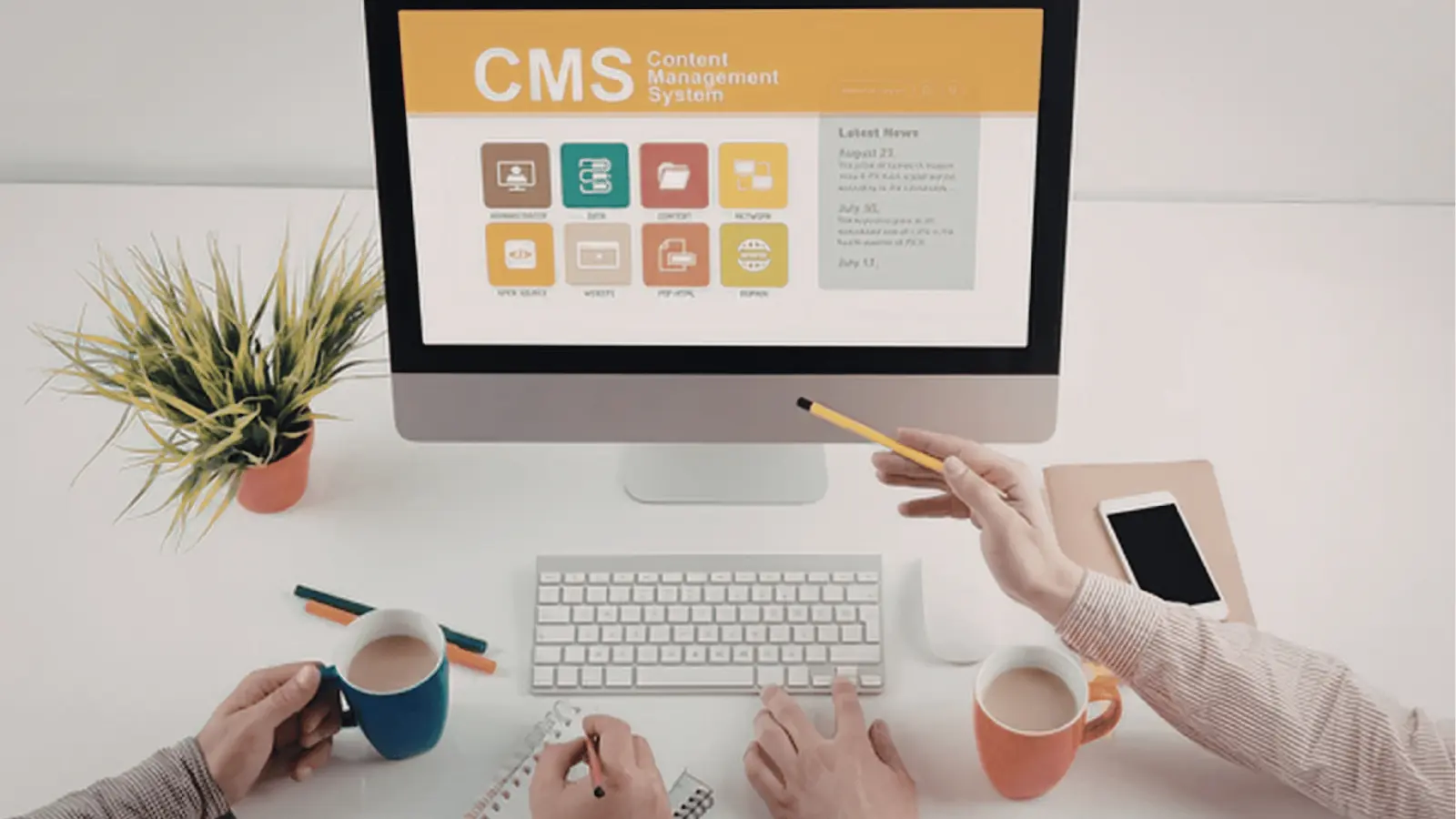 Desktop computer showing CMS screen on a tidy desk with hands and coffee