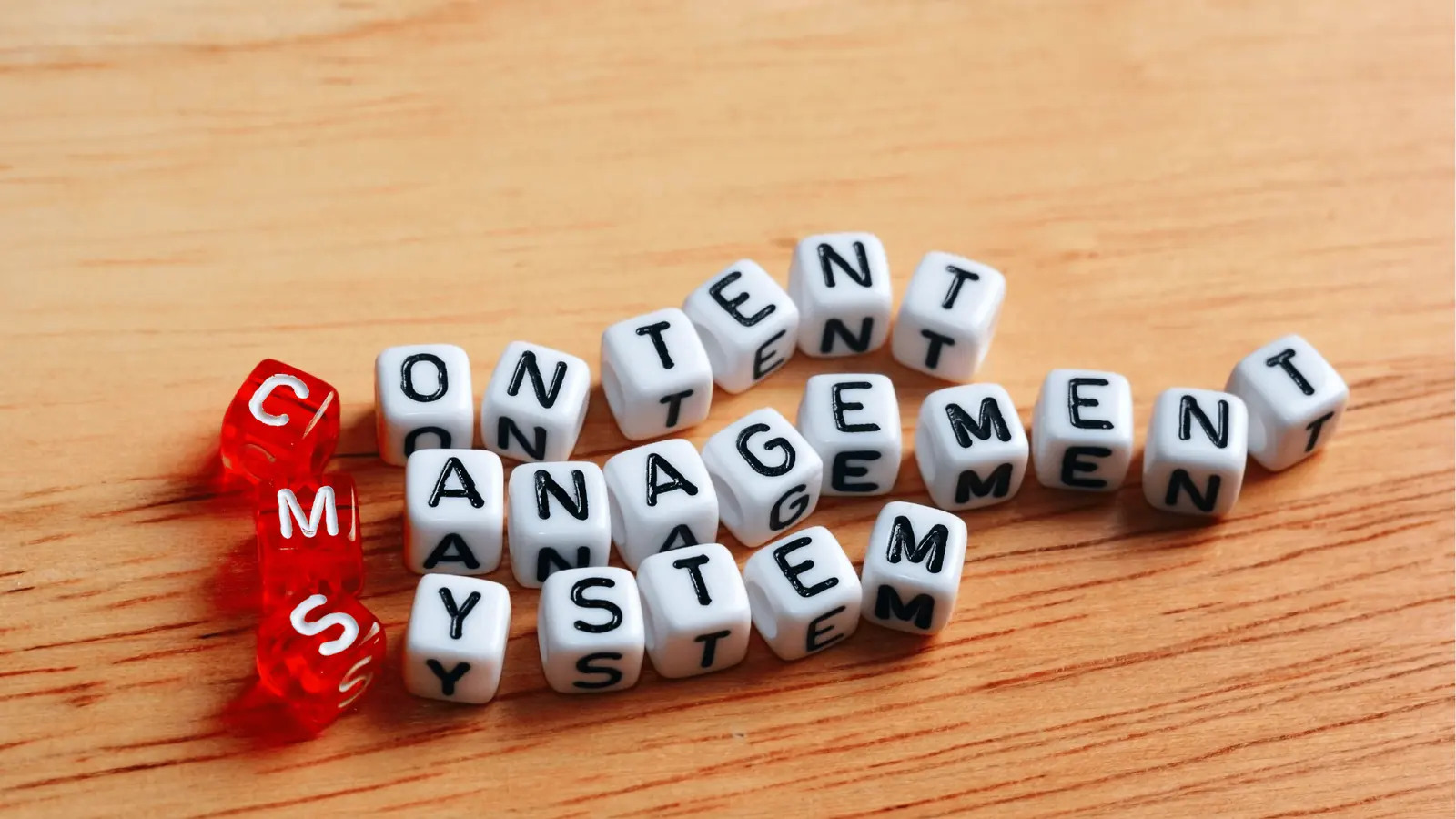 White letter cubes on wood spelling content management system with red CMS cubes for scheduling