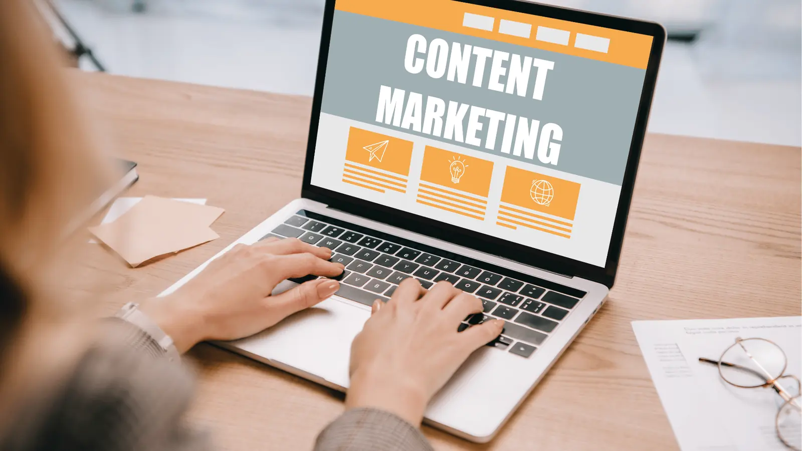 Hands typing on a laptop displaying a content marketing webpage on desk