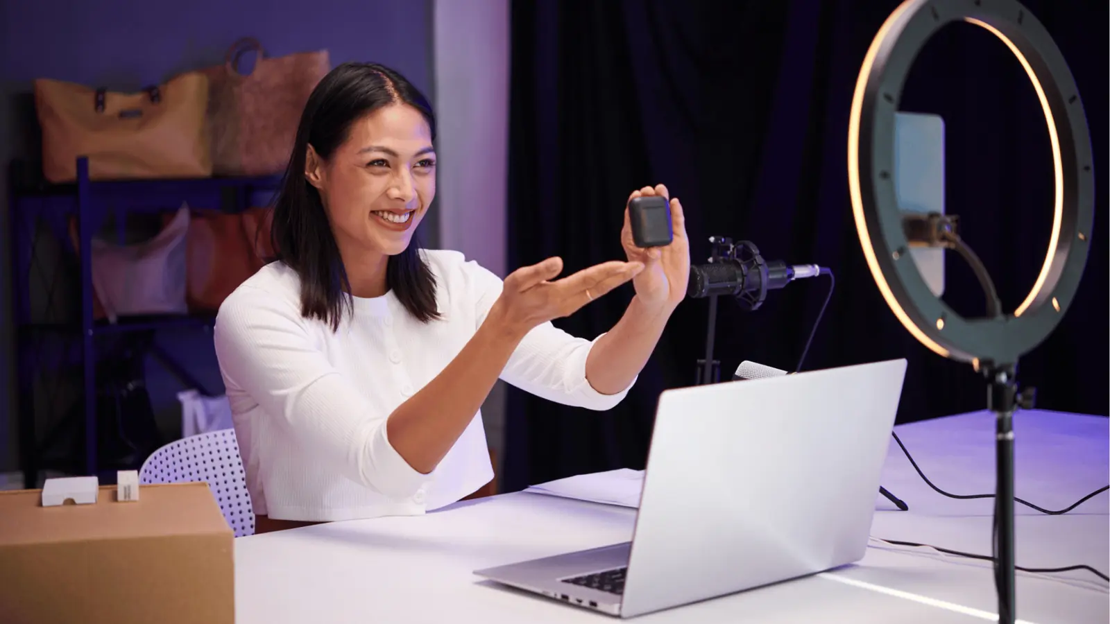 Woman demonstrating a small electronic product on camera with ring light