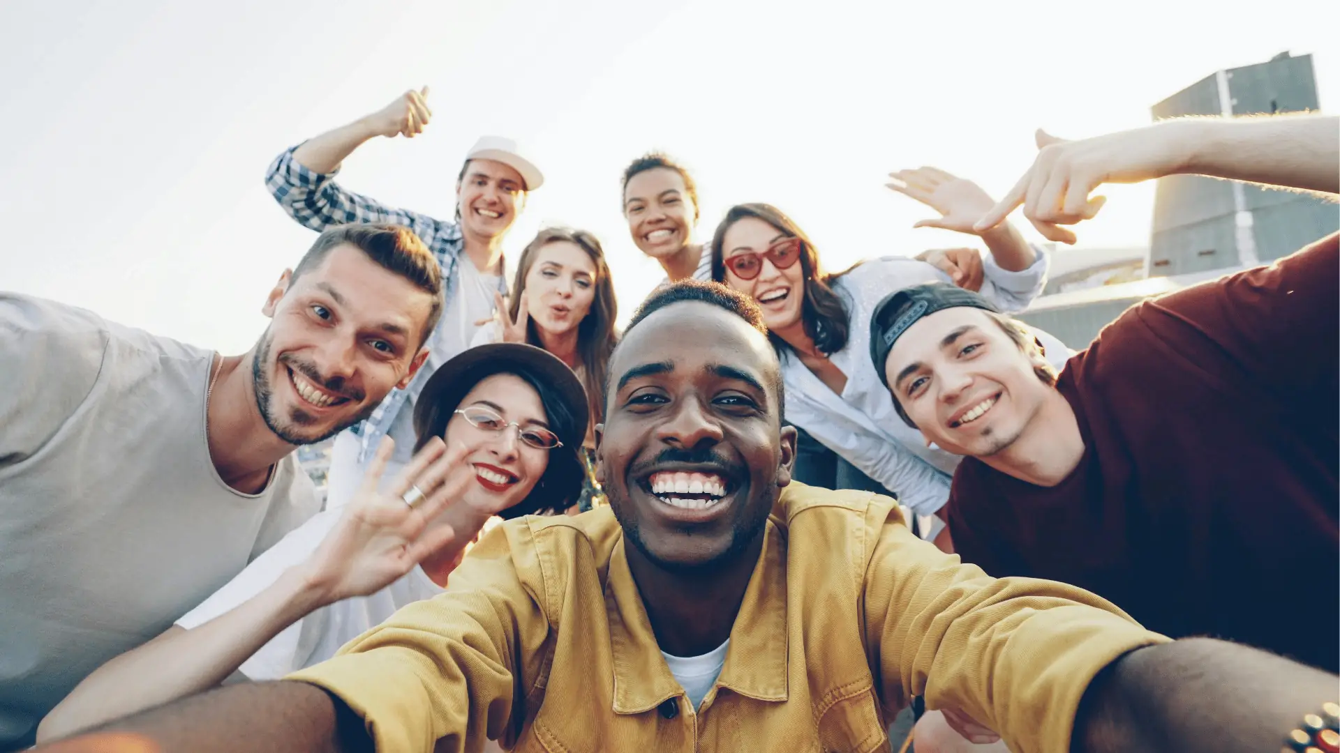 Group of smiling young adults taking a rooftop selfie together outdoors