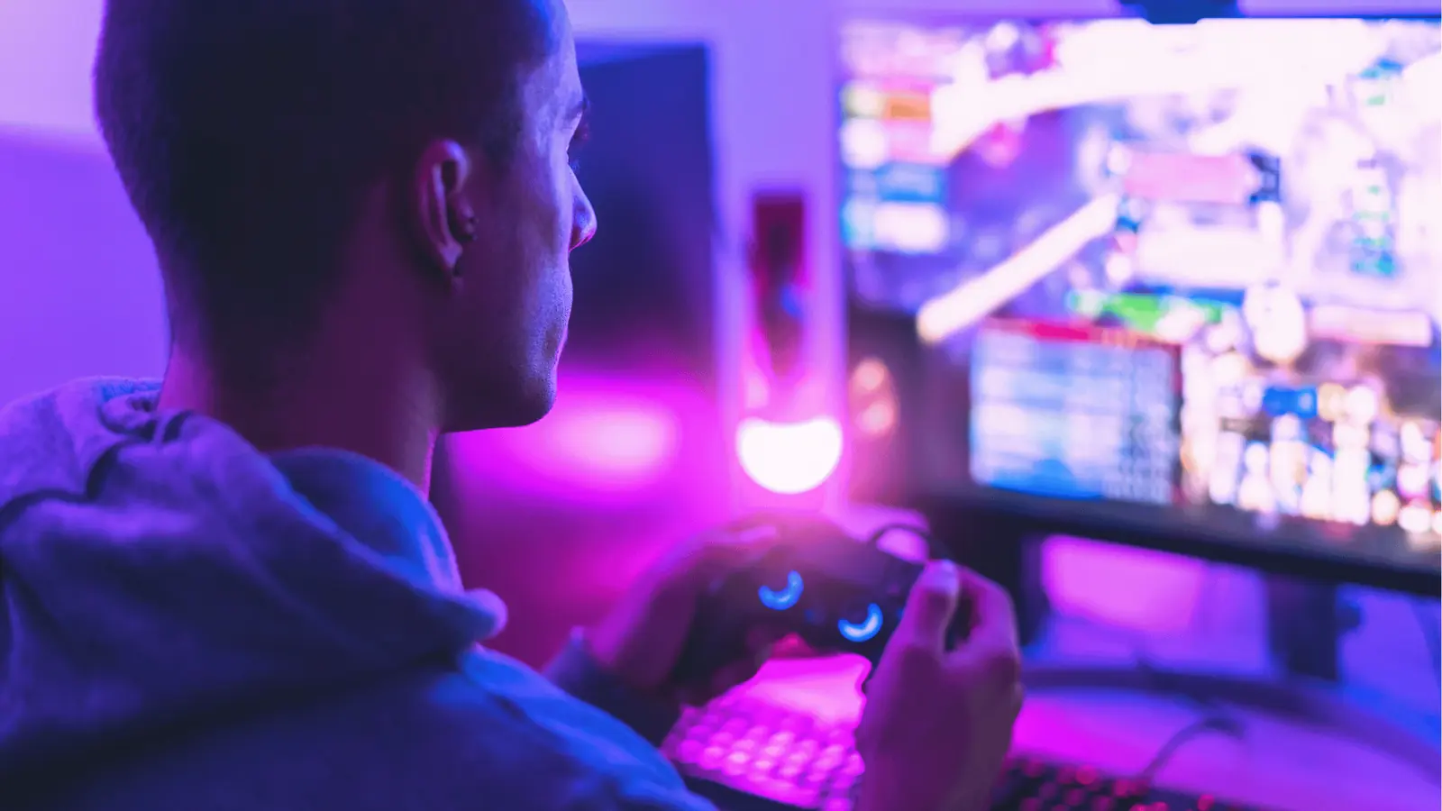 Person holding a game controller in front of colorful RGB monitor