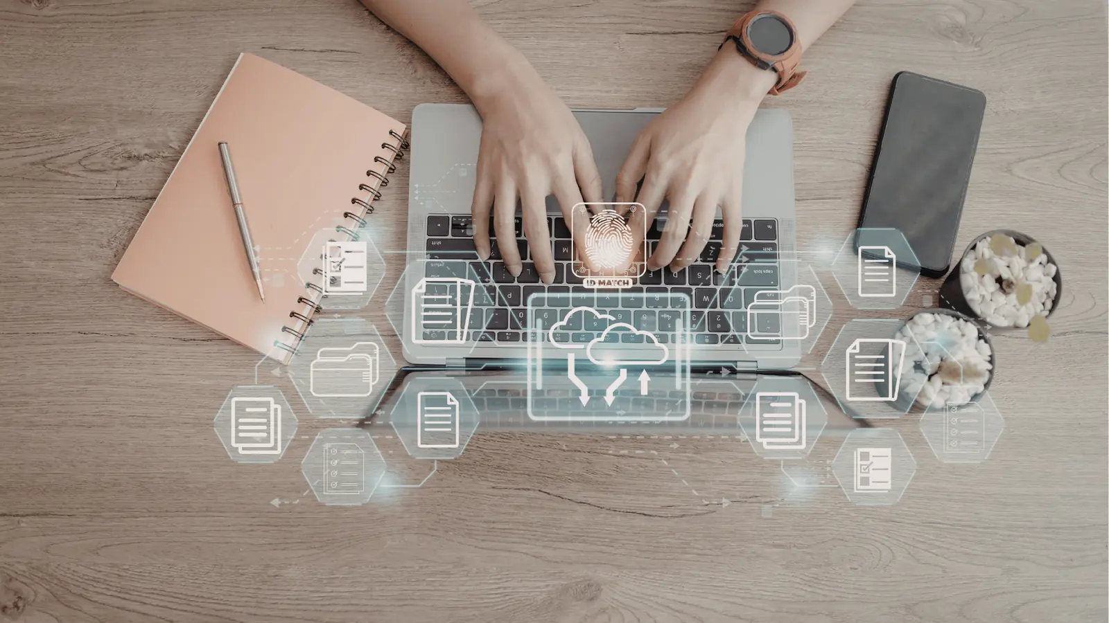 Top down view of hands typing on a laptop with cloud icons overlay