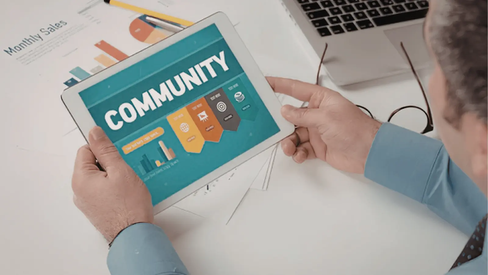 Man holding tablet that displays a teal COMMUNITY infographic at a desk for inbox management