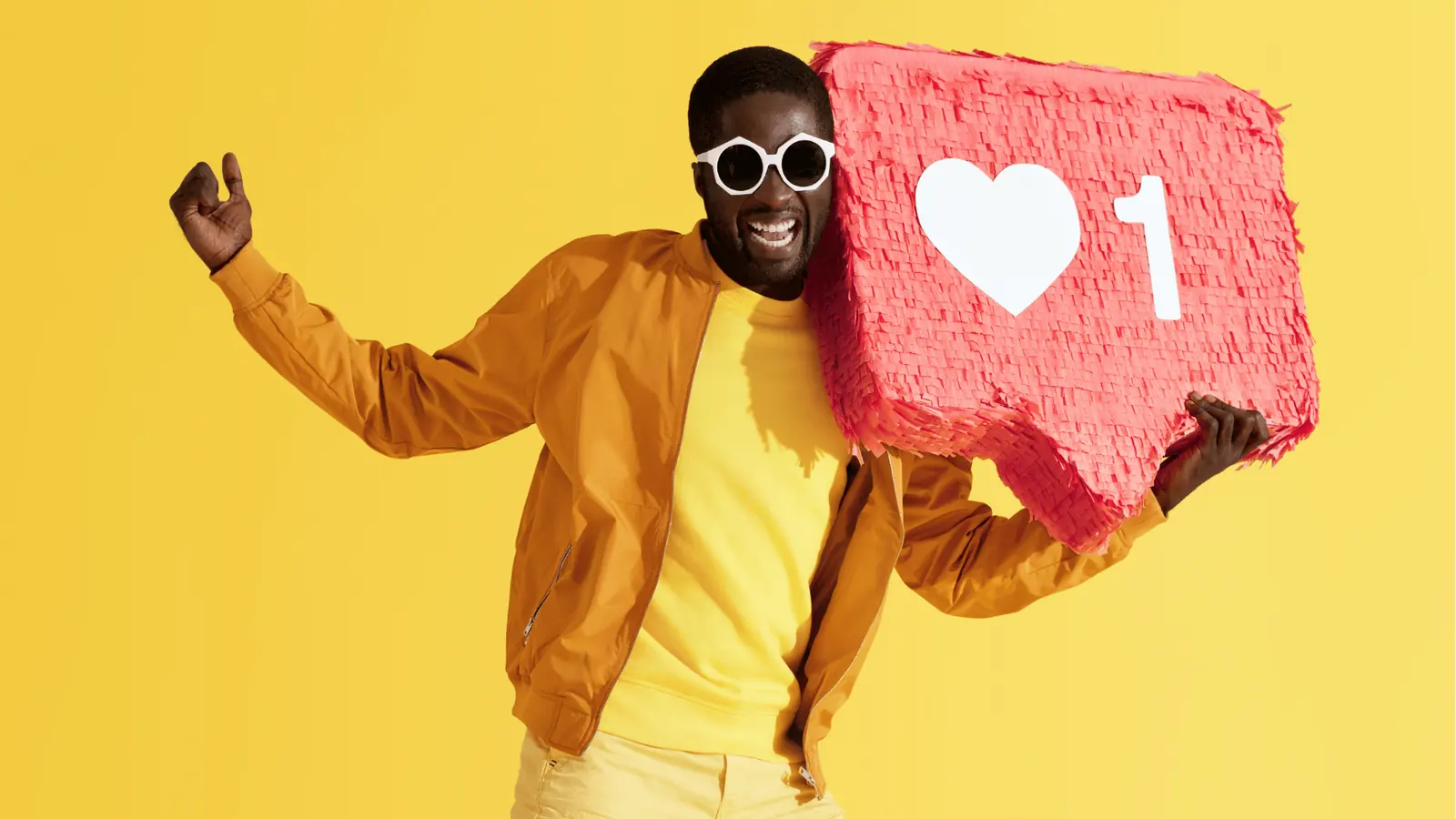 Smiling man wearing sunglasses holding a red like notification pinata