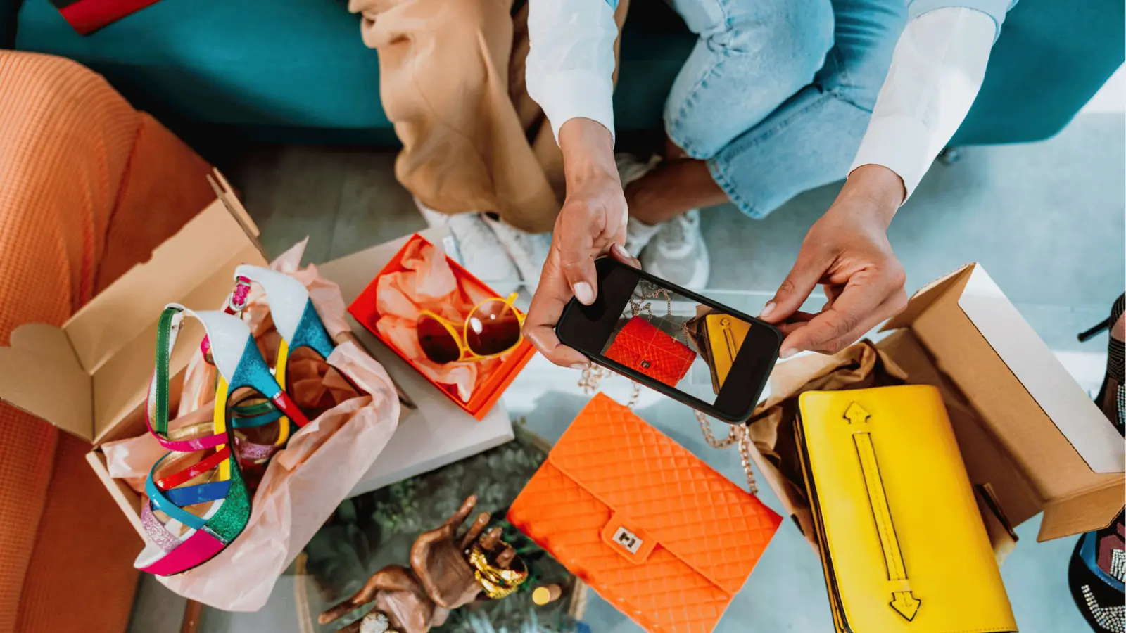 Hands photographing colorful handbags and shoes on a table