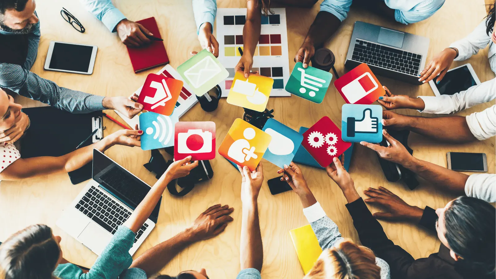 Overhead view of a team holding colorful social media and app icon cards