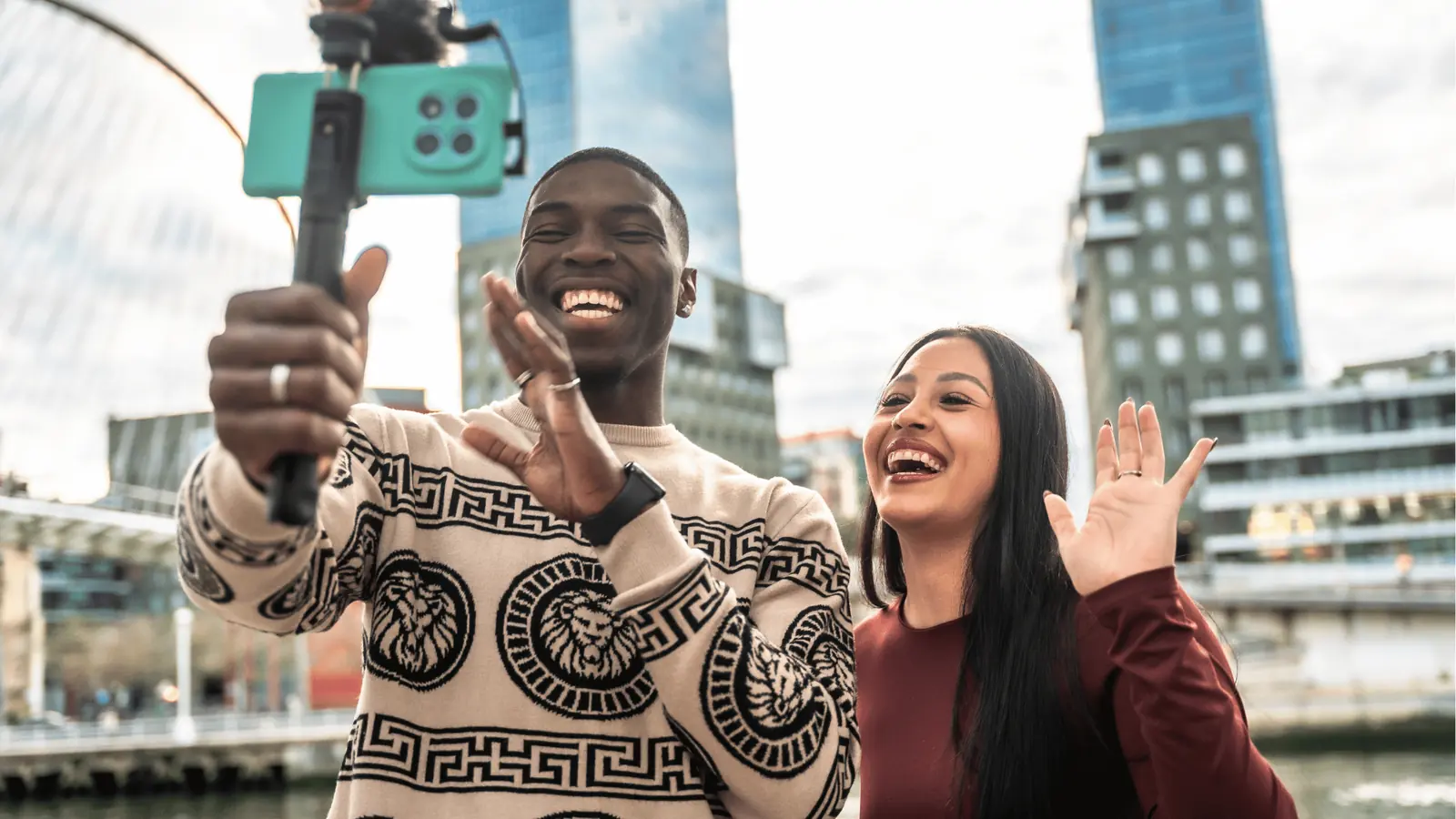Two people smiling and waving while recording a selfie video with smartphone for AI-assisted workflow