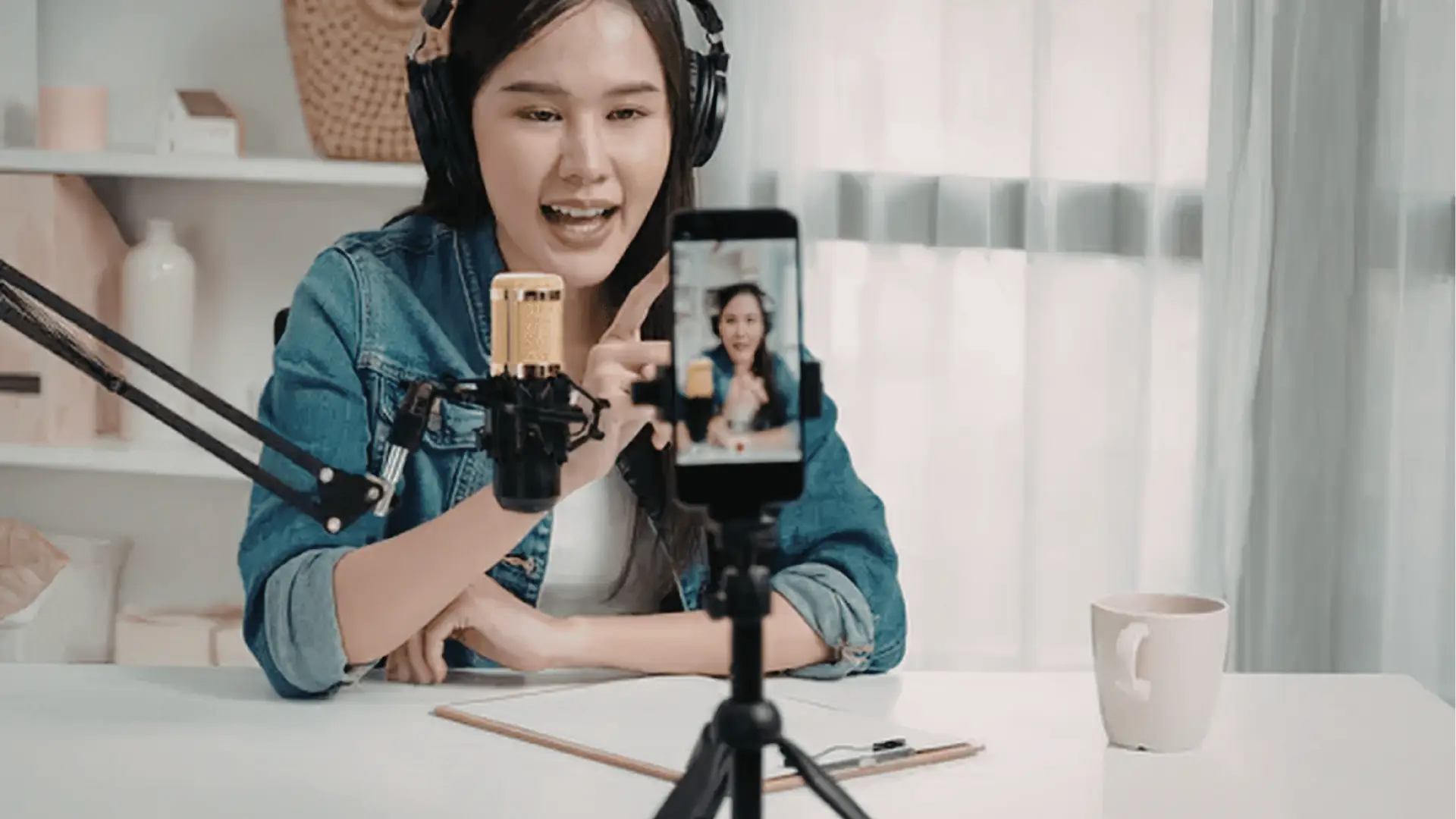 Young woman recording a smartphone video with microphone and headphones