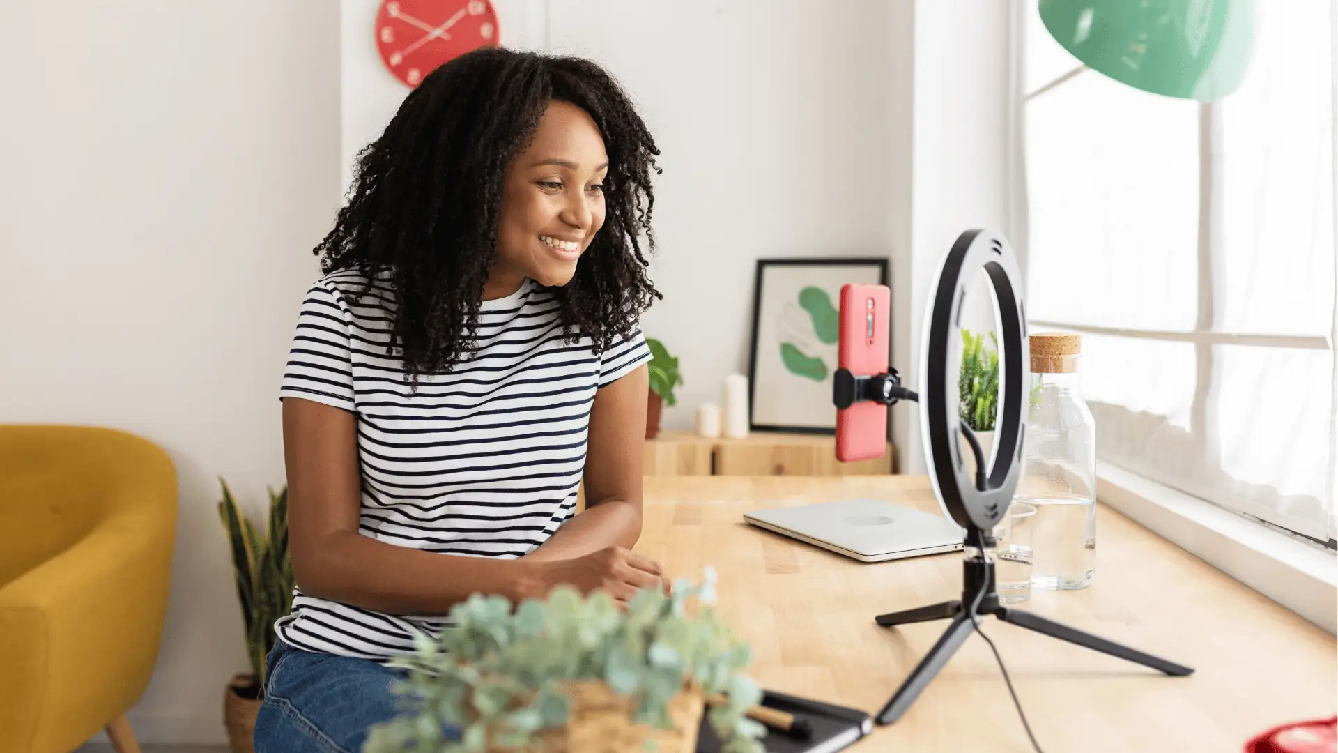 Smiling woman recording video at home desk with ring light for community management
