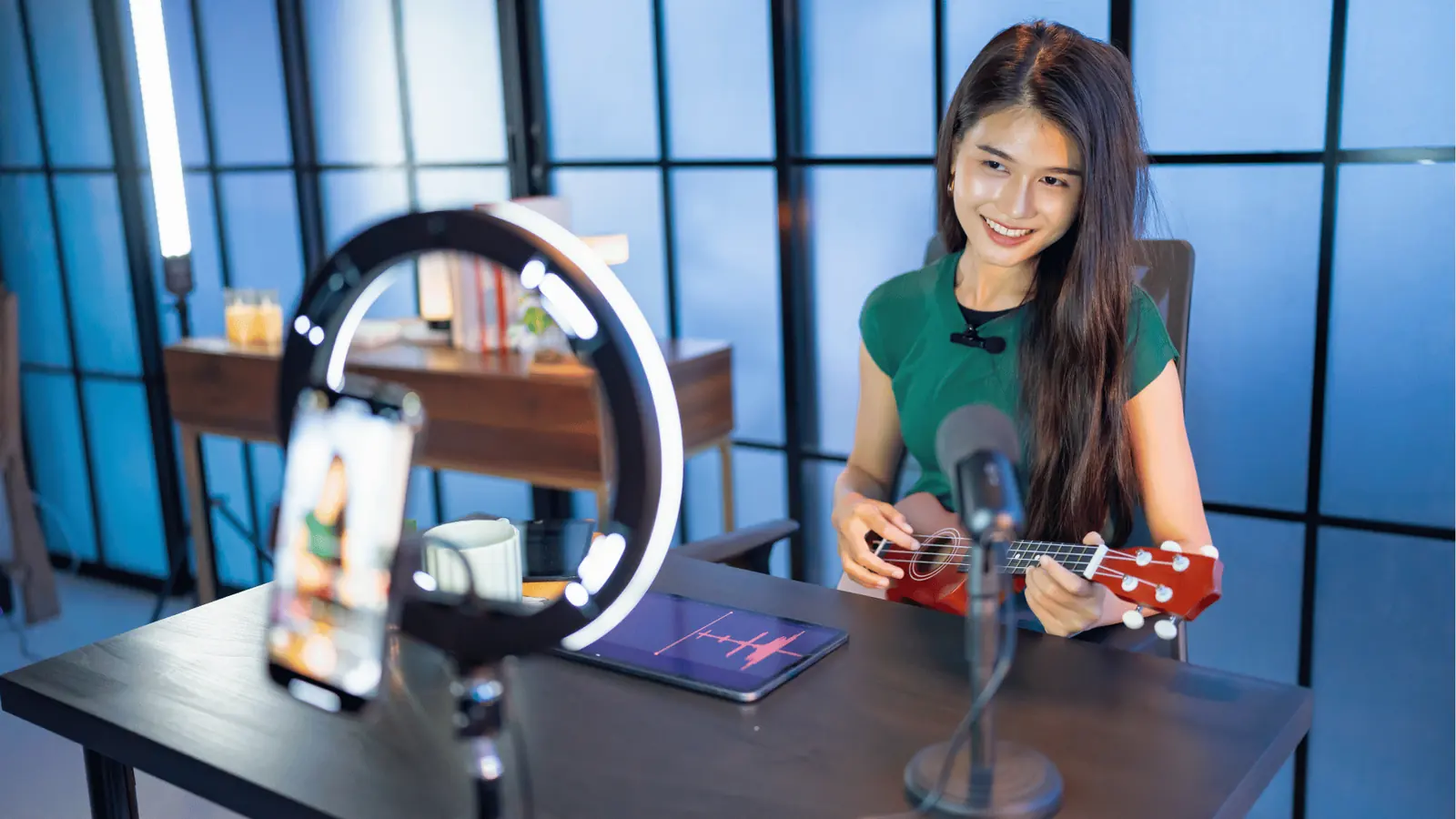 Young woman smiling while playing ukulele in a live-stream setup