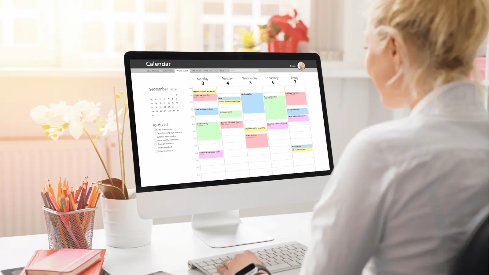 Person at desk viewing a weekly calendar on a desktop computer screen