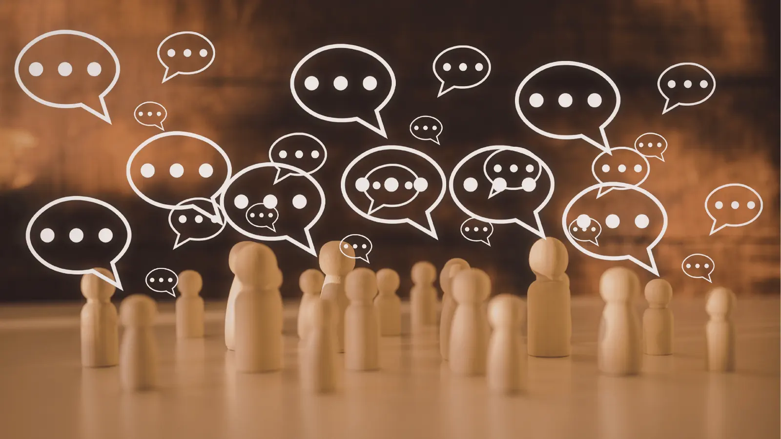 Wooden peg people with many drawn speech bubbles over blurred background