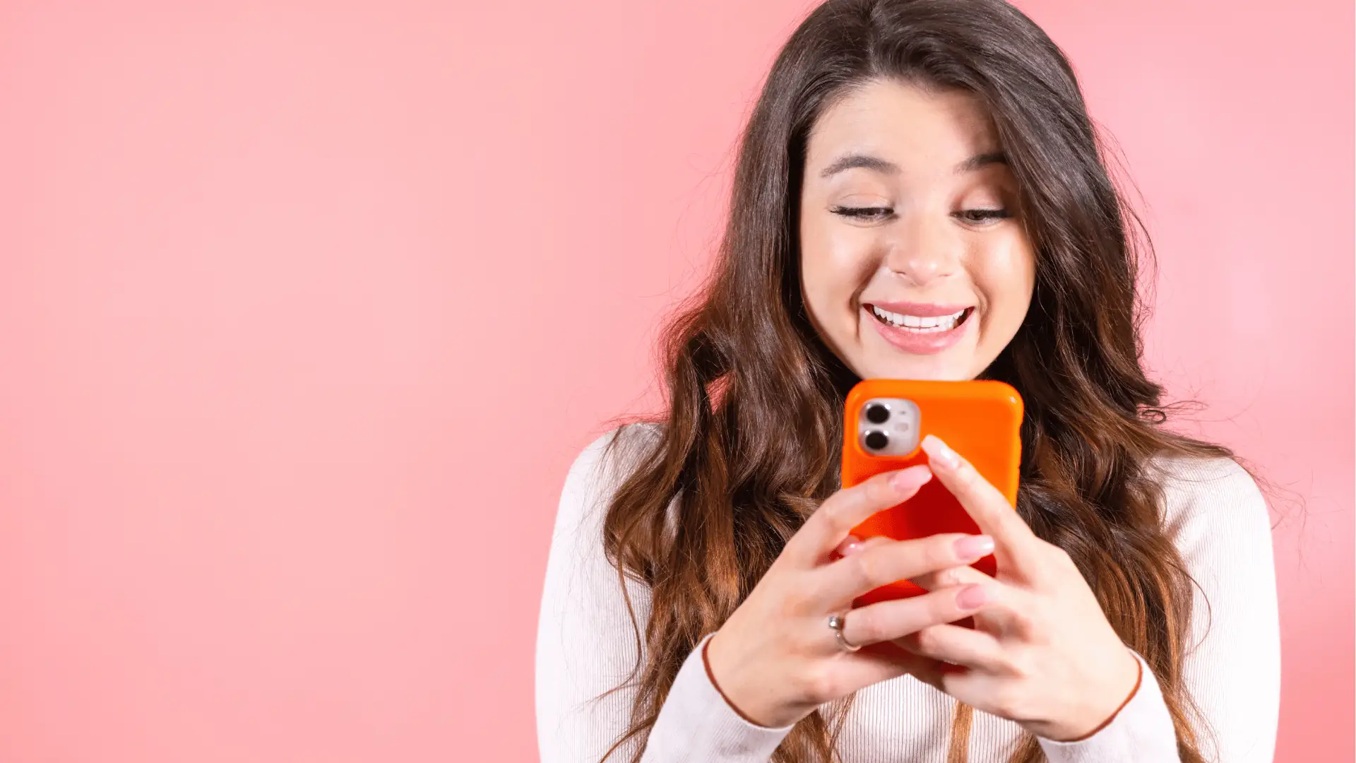Young woman smiling and looking at phone with orange case