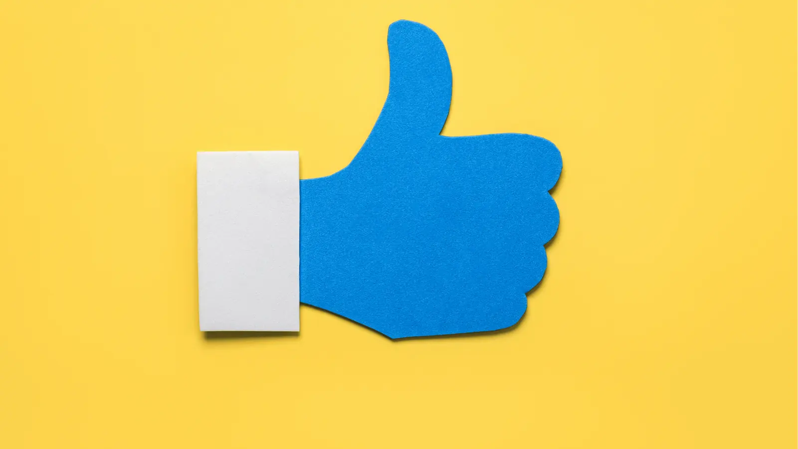 Blue thumbs-up cutout on yellow background with white cuff for content calendar