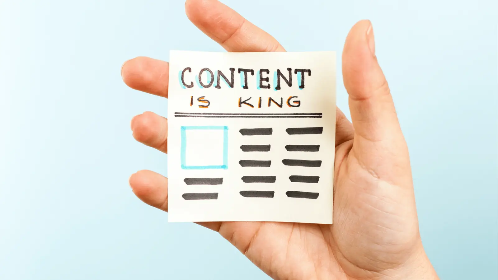 Hand holding sticky note reading 'Content is King' with drawn layout