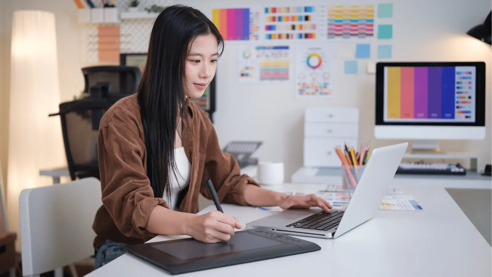 Woman using graphics tablet and laptop at a color-design workspace for approval workflow