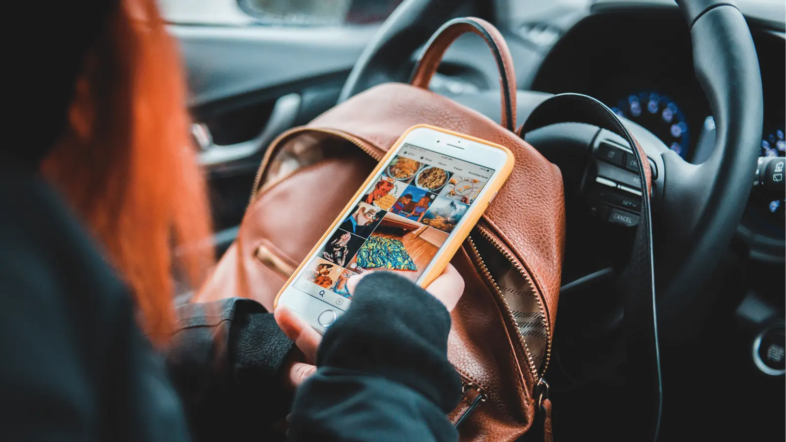 Person holding smartphone showing social media grid while sitting in a car for content calendar