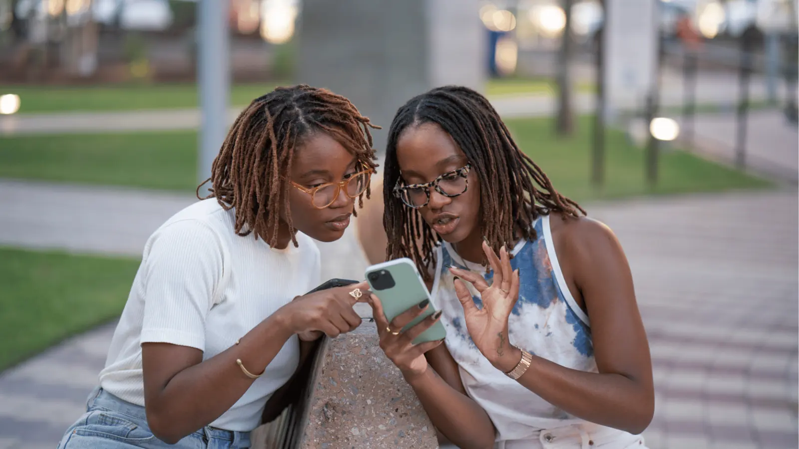 Two people leaning on a bench and looking together at a smartphone
